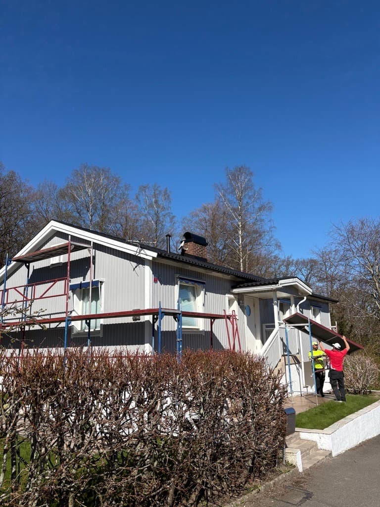 Bostadshus i Mölndal med ställning och målare under ommålning.
