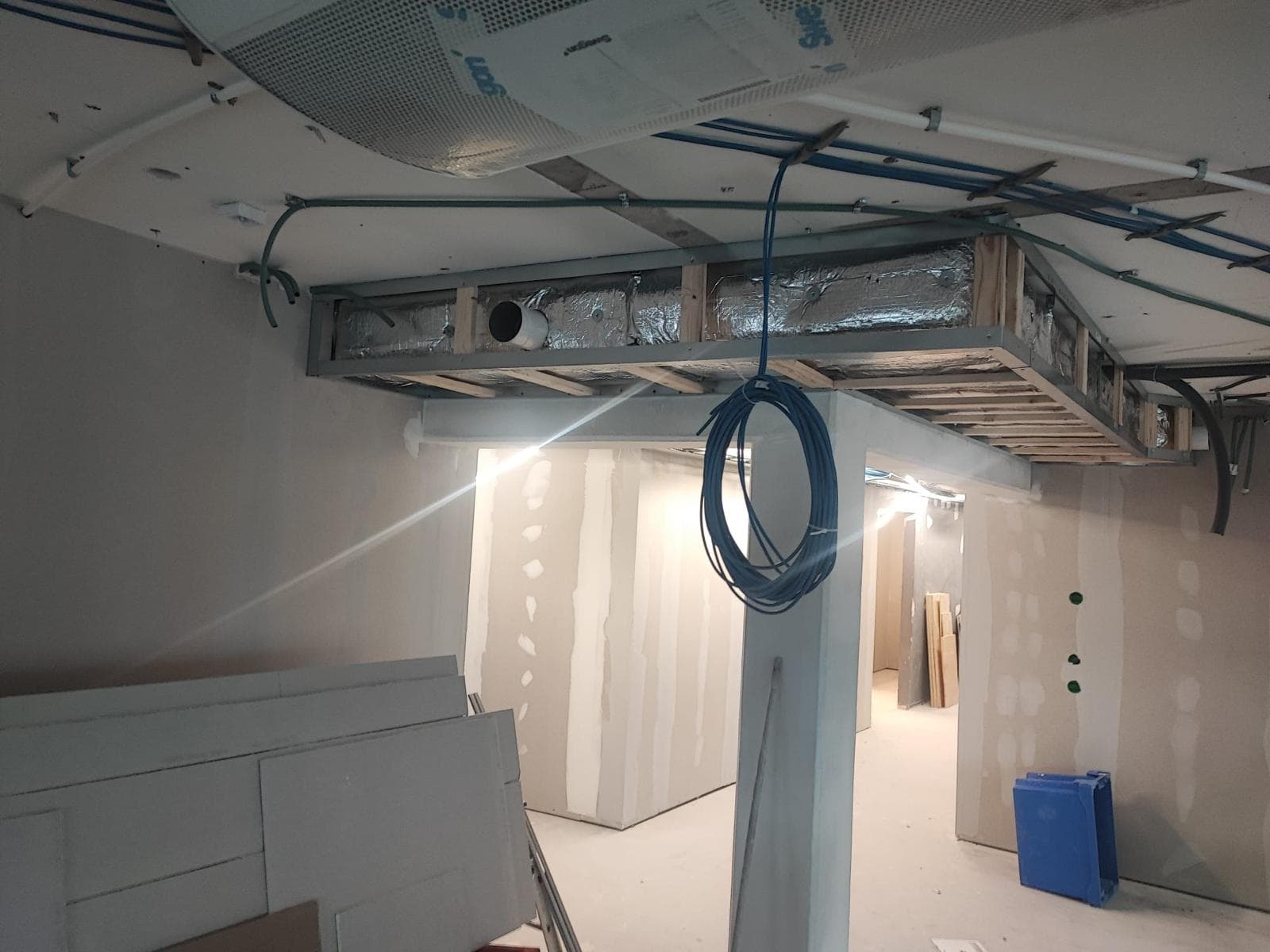 Rum under renovering med spacklade väggar och öppet tak.
