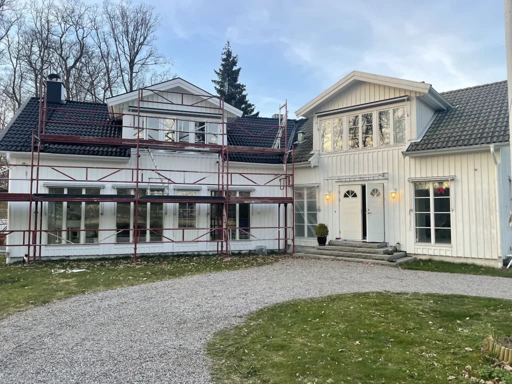 Vit träbyggnad med ställning under ommålning i Mölndal.